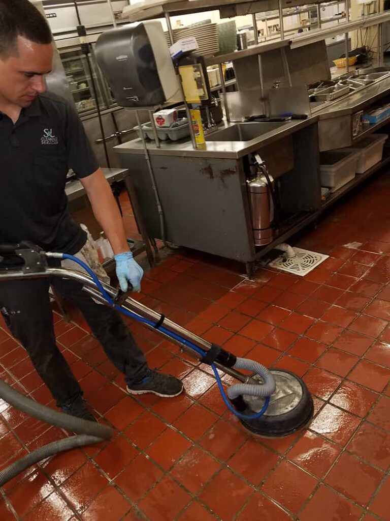 S&L Cleaning Service employee cleaning tile floor in a kitchen